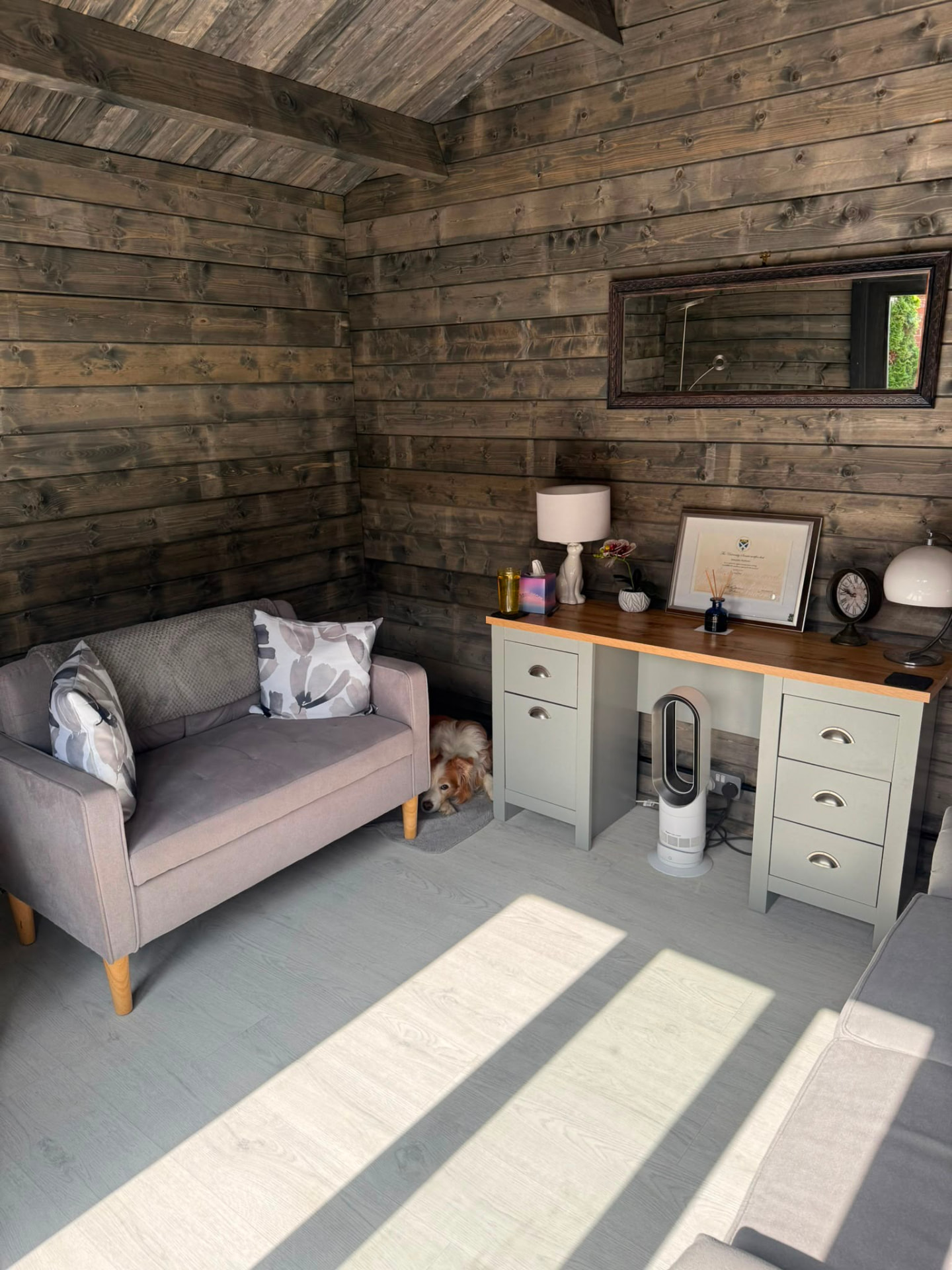 The cabin interior with timber walls, a comfortable sofa and a desk area