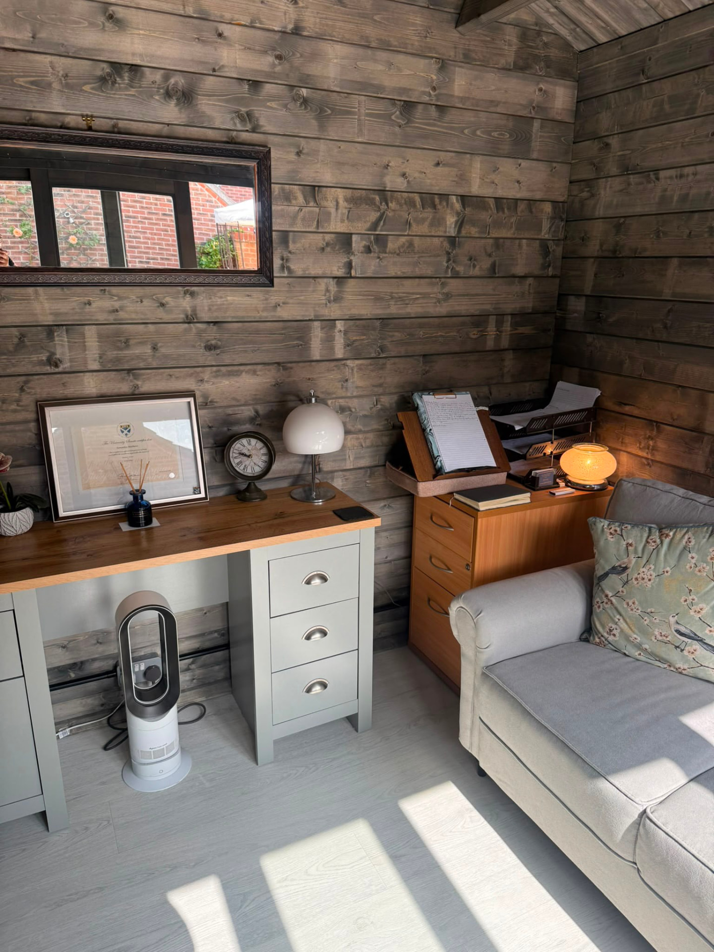 The cabin desk area with qualifications, a lamp and a comfortable sofa